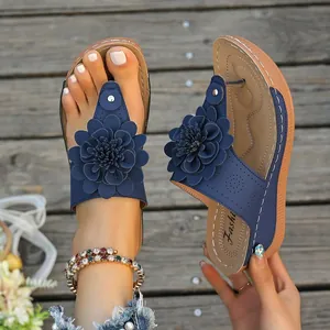 Detail view of blue wedge flip-flops with ornate flower and stitched insole pattern.