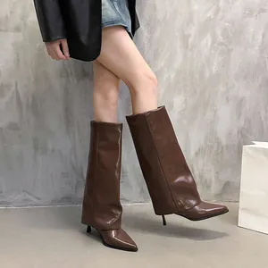 Stylish brown pointed-toe shark-lock boots with fold-over design worn by a model.