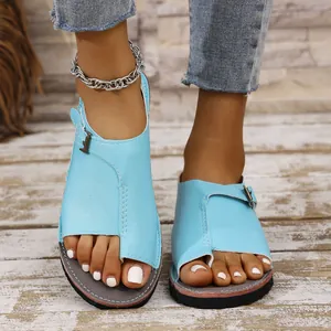 Close-up of light blue flat toe-ring sandals with metal buckles on feet