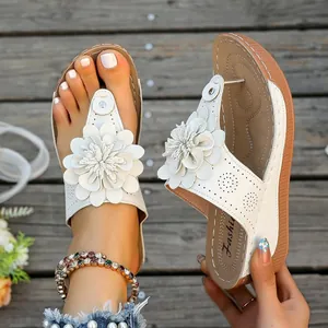 Detailed view of white platform thong sandals featuring large 3D flowers and laser-cut patterns