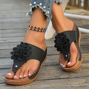 Detail shot of stylish black wedge sandals featuring a large decorative 3D flower
