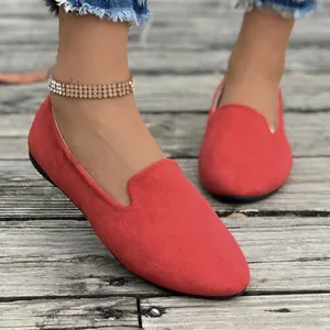 Detailed macro shot of red suede pointed toe flat loafers worn on wooden deck