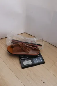 Professional detail shot of brown flat toe-loop sandal showing 190.5g weight on a digital scale