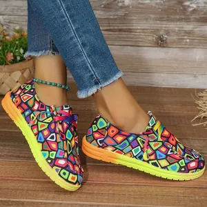 Nahaufnahme von farbenfrohen Canvas-Loafers mit Ethno-Muster auf rustikalem Holzboden.