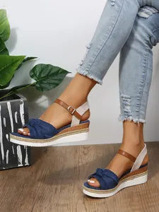 Primo piano dei sandali con zeppa blu navy decorati con fiocco e suola espadrillas.