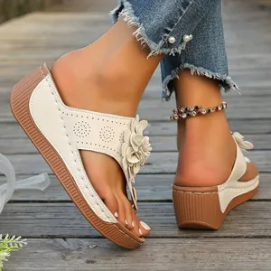 Detail view of stylish cream wedge thong sandals featuring floral accents and laser-cut patterns