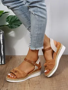 Dettaglio laterale di sandali platform marroni da donna con fiocco e suola espadrillas