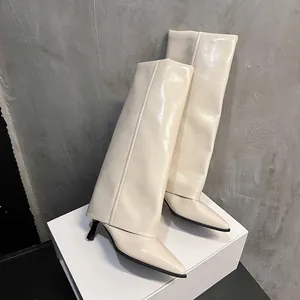 Close-up detail of cream pointed-toe stiletto boots featuring a stylish wide folded shaft