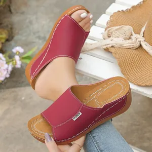 Close-up detail of red peep-toe wedge sandals with white stitching and Fashion label.