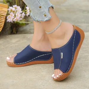 Close-up of navy blue platform peep-toe slippers with elegant white stitching detail.