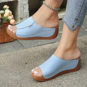 Detail view of light blue platform wedge slippers with open-toe design on feet.