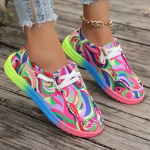Bunte Graffiti-Canvas-Sneaker mit Farbverlaufssohle auf einem Holzsteg fotografiert