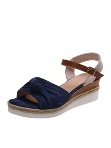 Vista dettagliata del sandalo blu con zeppa, fiocco elegante e suola platform intrecciata