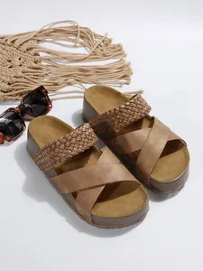 Primo piano di sandali platform bronzo metallizzato con cinturini intrecciati e suola spessa.