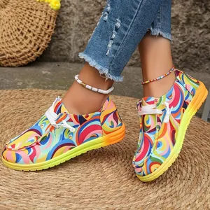 Nahaufnahme bunter Canvas-Loafer mit psychedelischem Wirbelmuster auf Strohmatte