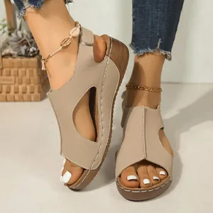 Detailweergave van beige sleehaksandalen met contraststiksels aan de voeten van model