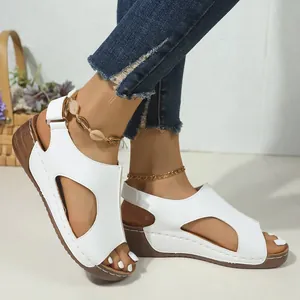 Detailopname van witte ademende wedgesandalen met uitgesneden ontwerp en klittenband