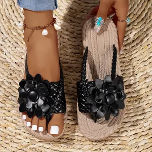 Detailweergave van zwarte platformsandalen met bloemdecoratie en gevlochten zool