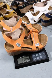 Vue détaillée d'une sandale compensée orange légère sur une balance pesant 228,9 g