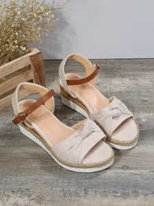 Dettaglio di sandali con zeppa e fiocco beige con suola in corda e cinturino