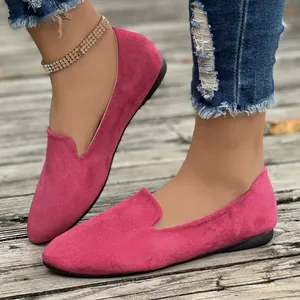 Detail view of fuchsia suede pointed toe loafers for women on a wooden background