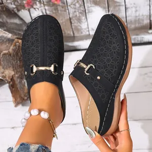 Detailed close-up of black floral cutout clogs with elegant gold buckle accents