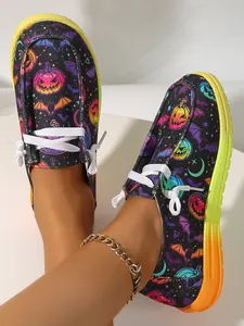 Detail view of colorful Halloween pumpkin and bat prints on black canvas slip-on shoes.