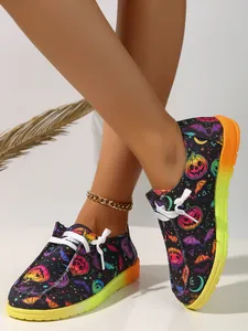 Close-up detail of Halloween pumpkin print canvas shoes with vibrant yellow gradient soles