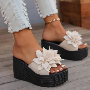 Close-up detail of the elegant white 3D flower embellishment on black platform wedge sandals