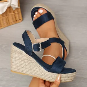 Close-up of blue suede wedge sandals with woven rope platform and ankle buckle strap.