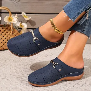 Detailed view of navy blue laser-cut mules featuring a metal buckle and comfort thick sole