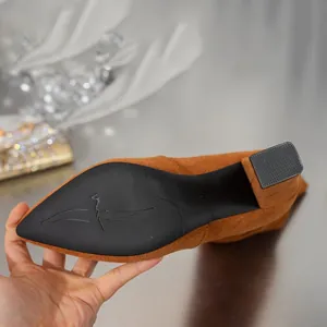 Detail van de antislipzool en de blokhak van bruine suède slouchy hoge dameslaarzen