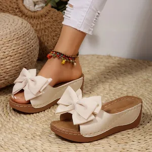 Elegante beige Plateau-Sandalen mit großer Stoffschleife für den Sommer im Detail.