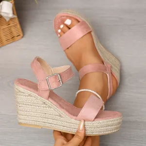 Detailed macro view showing pink suede wedge sandals with woven rope platform heels.