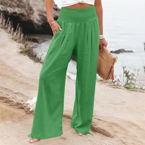 Dettaglio dei pantaloni larghi in lino verde a vita alta in ambiente spiaggia