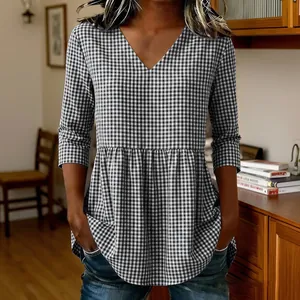 Detail shot of a women's v-neck gingham blouse with a stylish peplum ruffle hem.