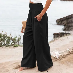 Dettaglio dei pantaloni casual neri a gamba larga da donna su una spiaggia soleggiata