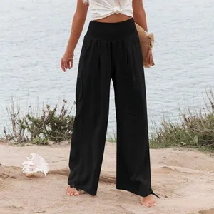 Dettaglio di pantaloni neri a gamba larga a vita alta da donna in riva al mare