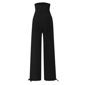 Dettaglio dei pantaloni neri a vita alta con fascia elastica a punto smock e gamba larga
