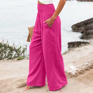 Vista completa di pantaloni larghi fucsia indossati da una modella sulla spiaggia