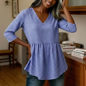 Detail view of a blue and white gingham v-neck top with a flared peplum hem.