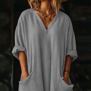 Detalle de vestido bohemio gris suelto con bolsillos laterales y escote en V.