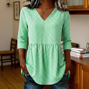 Detailed view of green gingham V-neck tunic with flared peplum hem and 3/4 sleeves.