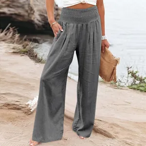 Detail view of women's casual grey wide-leg cotton linen trousers on beach background