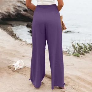 Vista posteriore di pantaloni larghi viola a vita alta per donna in spiaggia.