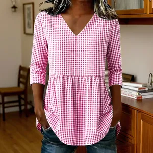 Detail view of casual pink gingham top featuring a V-neck and stylish ruffled peplum hemline