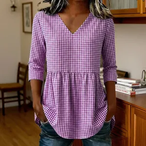 Detail showing the purple and white gingham pattern and peplum hem of the V-neck top.