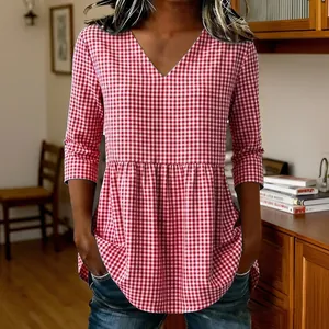 Detailed view of red and white gingham V-neck top featuring loose fit and peplum hem.