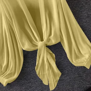 Detail view of yellow sheer chiffon sun-protection blouse with tie-front knot design