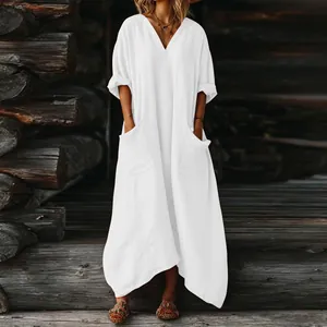 Elegante vestido maxi boho blanco holgado con bolsillos sobre fondo de madera rústica